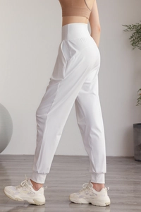 Dettaglio dei pantaloni da yoga bianchi a vita alta con tasche laterali e polsini a costine