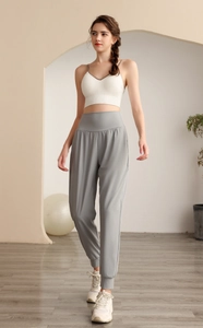 Dettaglio dei pantaloni sportivi grigi a vita alta e canotta sportiva bianca con scollo a V