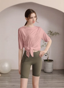 Détail du t-shirt de yoga rose avec ourlet noué et short de cyclisme olive à taille haute