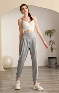 Pantaloni sportivi in nylon a vita alta con canotta bianca in una palestra di yoga moderna