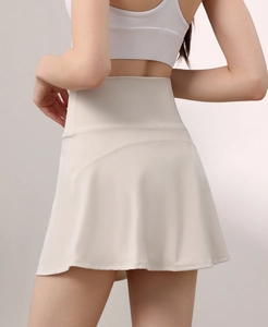 Detail view of high-waist beige tennis skirt showing elastic fabric and A-line curved seam