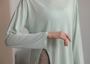 Détail du haut de yoga vert menthe montrant le tissu respirant et le design à fente latérale