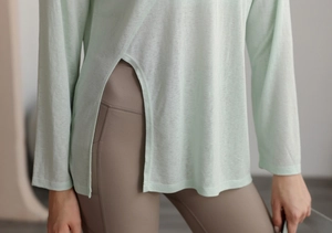 Détail du haut de yoga vert clair montrant la fente latérale haute et le tissu respirant