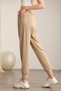 Detail view of khaki high-waisted nylon joggers with elastic cuffs and side pockets
