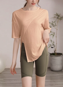 Détail du haut de sport ample orange avec ourlet fendu irrégulier et short de yoga