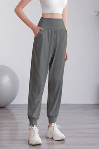 Dettaglio dei pantaloni sportivi in nylon a vita alta verde oliva con tasche laterali