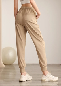 Rear view of high-waist loose joggers in beige featuring elastic cuffs and dual back pockets