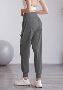 Dettaglio dei pantaloni sportivi a vita alta color oliva con tasche laterali e polsini