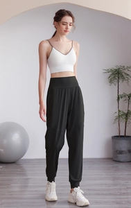 Détail du jogging vert à taille haute et brassière blanche dans un studio de yoga