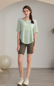 Detail view of mint green tencel yoga top with asymmetric straps and olive green gym shorts
