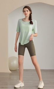 Detail view of light green cut-out yoga t-shirt and olive high-waist cycling shorts