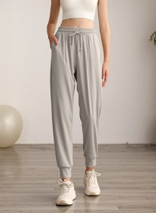 Detail view of light grey high-waist joggers with drawstring and cuffed ankles for yoga