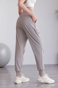 Dettaglio dei pantaloni da yoga a vita alta con tasche laterali e polsini a coste taupe
