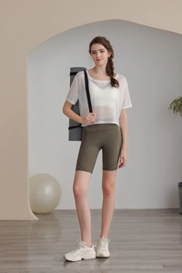 Dettaglio del top da yoga in mesh bianco con pantaloncini fitness verdi a vita alta