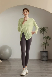 Détail du haut de yoga vert clair à ourlet asymétrique et legging gris ajusté