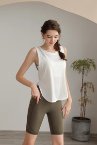 Dettaglio del gilet sportivo bianco largo e pantaloncini da ciclista verde oliva per yoga