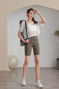 Dettaglio del top da yoga bianco e pantaloncini verde oliva con tappetino da yoga