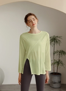 Détail du haut de yoga vert avocat avec tissu transparent et fente irrégulière à l'ourlet
