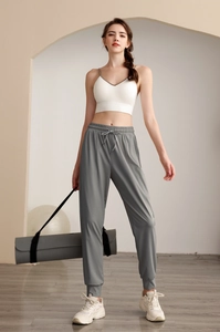 Nylon high-waist loose joggers with white strappy sports vest in minimalist gym setting