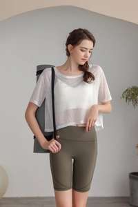 Dettaglio del top da yoga bianco ampio abbinato a pantaloncini sportivi verde oliva
