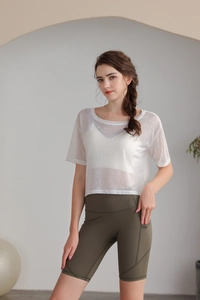 Dettaglio del top yoga bianco semitrasparente e dei pantaloncini biker a vita alta oliva