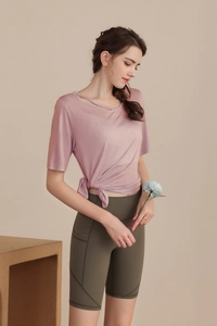Detail view of pink yoga t-shirt with waist knot and olive green shorts with side pockets