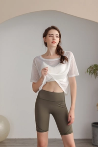Dettaglio del top da yoga bianco semitrasparente e pantaloncini da ciclista oliva sul modello