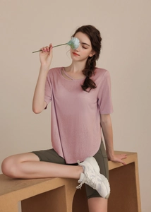 Pale pink short sleeve yoga top with cross-neck strap detail and curved hemline