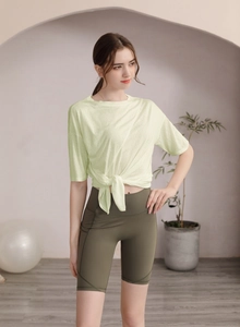 Détail de l'ensemble de yoga avec haut jaune noué et short cycliste taille haute vert olive