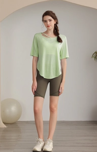 Close-up of light green yoga top with hollow-out cross neck and olive bike shorts