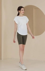 Detail of white short-sleeved workout top and olive green high-waist yoga shorts on model