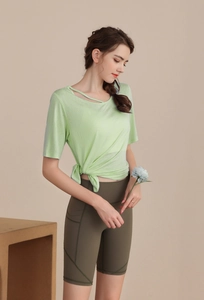 Detail of light green yoga top featuring a cutout neck and side knot with olive biker shorts