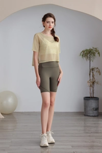 Dettaglio del top in mesh giallo chiaro e degli shorts da yoga a vita alta verde oliva
