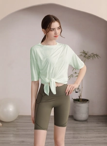 Détail du t-shirt de yoga vert clair avec nœud latéral et short de cycliste olive