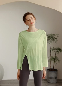 Détail de la fente latérale et du tissu texturé du haut de yoga vert clair à manches longues