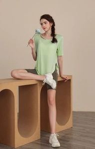 Detail of light green yoga t-shirt with cross strap neckline and side slit design