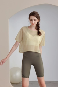Dettaglio del top da yoga in rete e dei pantaloncini da ciclista verdi a vita alta con tasche