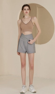 Détail d'un short de fitness gris à taille haute avec un design croisé élégant sur modèle