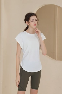 Close-up of a white breathable short sleeve yoga top with side pockets on green shorts