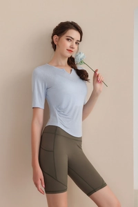 Détail d'un haut de yoga bleu clair à col en V avec plis et d'un short de cycliste vert