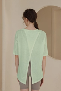 Detail view of women's mint green sports top featuring an elegant back cross slit design