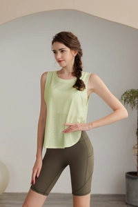 Dettaglio della canotta da yoga verde chiaro e pantaloncini a vita alta verde oliva con tasche
