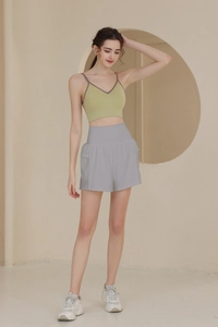 Detail der grauen Sporthose mit hoher Taille und grünem geripptem Crop-Top