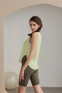 Dettaglio del top sportivo verde chiaro con spacchi laterali e pantaloncini da yoga a vita alta