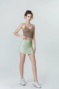 Detail of high-waist green pleated tennis skirt and ribbed brown crop top set