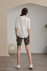 Back view of a breathable white yoga T-shirt and olive green cycling shorts on a model