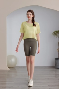 Dettaglio del top da yoga in mesh giallo e pantaloncini biker verde oliva con tasca