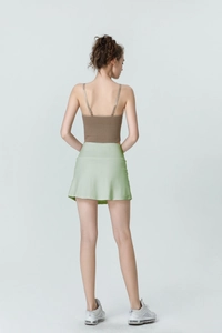 Back view of high-waisted green sports skirt with built-in shorts and brown crop top