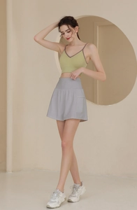 Detailansicht von grünem Sport-Oberteil und hellgrauen High-Waist-Shorts mit Seitentasche