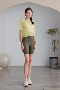 Dettaglio di un top da yoga in mesh giallo limone con pantaloncini da ciclista verdi